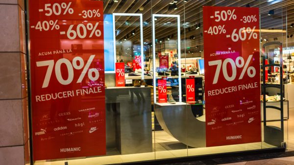 Discount, sale signs, red poster offer, mock up advertise display frame over clothes in shopping mall or department store for show promotion product at AFI Cotroceni Mall from Bucharest, Romania, 2020